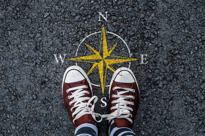 Person standing in tennis shoes facing north (identified by a compass painted on the gravel ground)